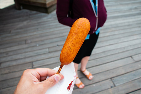 Plain Brown Corndog Hold in a Hand on a Wooden Pierの写真素材