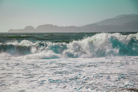 Energetic Waves Arriving on the Coast of South Bay and Golden Gate With Hills in the Horizon and White Spray and Foam of the Powerful Wavesの写真素材
