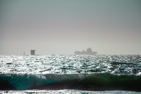 Hazy Sea View With a Silhouette of a Container Ship on the Horizon on a Sunny Dayの写真素材