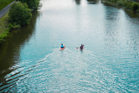 Kayaks Rowing on the River Stream Along a Park