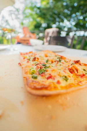 Fresh French Tarte Flambe Flammekueche with CrÃ©me Fraiche Cheese Bacon Cubes and Spring Onions on a Wooden Tablet Tray Close Upの写真素材