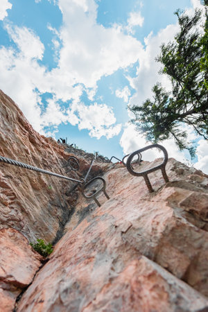 Via Ferrata Climbing Path with Metal Wire and Steps Going Up a Mountain Wallの写真素材