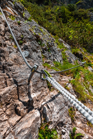 Carabiner Fixed Safly on a Mounted Steel Climbing Cable Along a Natural Stone Rock Wallの写真素材