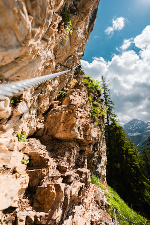 Steel Wire Cable Leading Up a Climbing Path on a Stony Mountain Cliffの写真素材