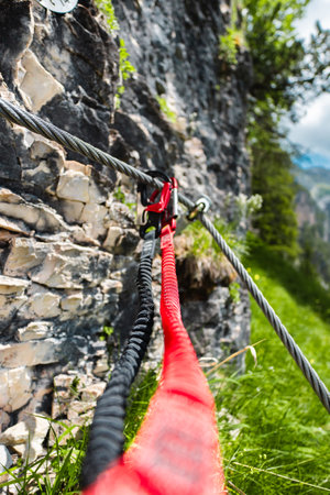 Double Carabiner with Safety Rope Mounted on a Steel Wire Cable Close to a Stone Climbing Wallの写真素材