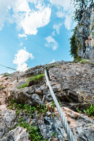 Straight View Up a Via Ferrata Steel Wire Cable Going Along a Stone Wallの写真素材
