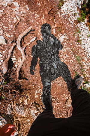 POV VIew of a Hikers Shadow Standing on a Stony Hiking Trailの写真素材