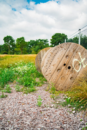Wooden Cable Reel Standing Near a Mesh Fence on a Construction Site on a Development Project in Natureの写真素材