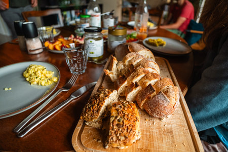 Breakfast Table With Cut Slices of Fresh Bread on a Wooden Board Fruits and Scrambled Egg Ready to...
