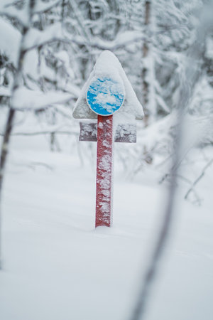 Sign Post with a Snow Mobile Symbol Covered with Snow in a Cold Winter Forestの写真素材