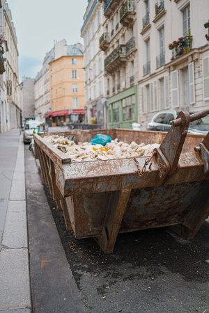 Decayed and Weathered Construction Container Filled with Waste Standing on the Street of a City