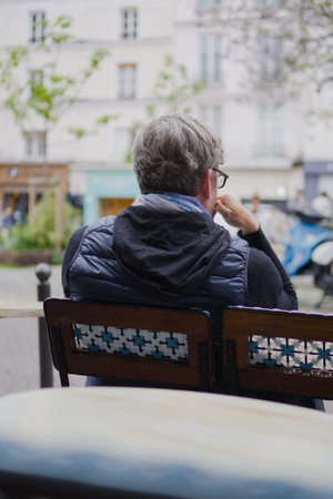 Older Man Sitting in a Chair in a CafÃ© Outside Thinking about Life while Observing the Cityの写真素材