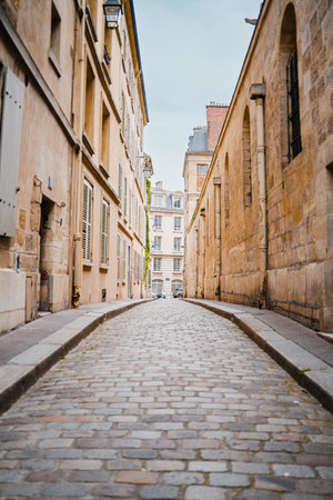 Small and Narrow Alley Cobblestone Street with a Short Sidewalk Guided by Weathered Stone Buildings in France parisの写真素材