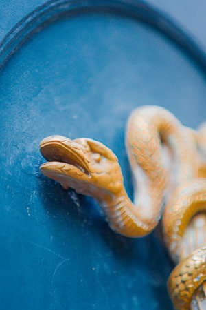 Close Up View of a Golden Snake Sculpture Infront of a Blue Backgroundの写真素材