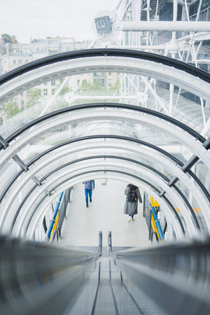 Transparent Glass Tunnel with an Escalator Leading Downwards in a Public Spaceの写真素材