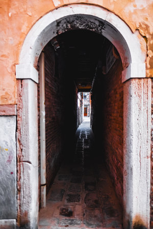 Explore the captivating, narrow alleyway in Venice, Italy, with its ancient architecture and charming atmosphere, inviting curiosity and wonder.の写真素材