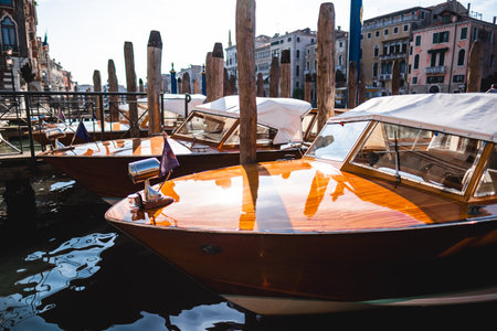 Stylish wooden water taxis docked at a scenic Venetian canal, capturing the elegance of Venice's historic architecture and tranquil waterways. Perfect for travel or architecture enthusiasts.の写真素材
