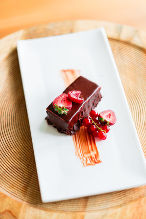 Delicious chocolate dessert beautifully garnished with fresh strawberries and red currants, presented on a white plate, offering an enticing and sophisticated gastronomic delight for gourmet diningの写真素材