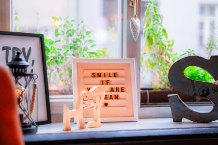 A cozy home interior is decorated with motivational quotes, a charming lantern, and a wooden figurine on a sunlit windowsill. Lush greenery brightens the peaceful and inspiring atmosphere.の写真素材