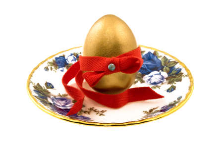 Golden testicle on a plate decorated with red ribbonの写真素材