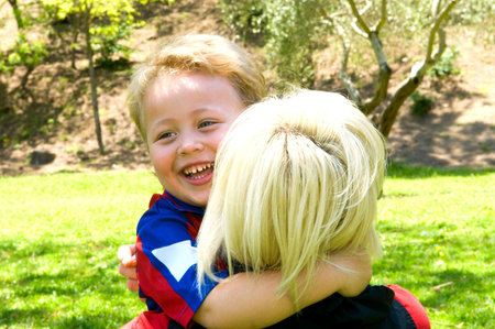 	The boy hugs mom by the neck and funny laughsの写真素材