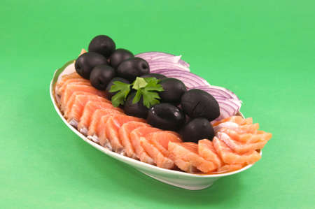 Salmon chopped on flat pieces adorned with black olives and onionsの写真素材