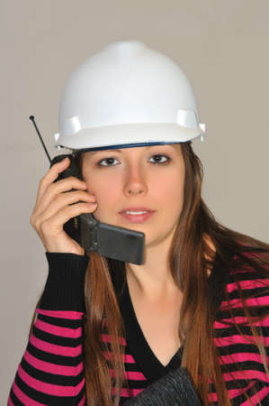 A girl in a white construction helmet, said by mobile phone with a customerの写真素材