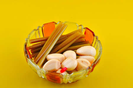 Pickled garlic and wild garlic stems lie in a small salad bowl of colored glassの写真素材