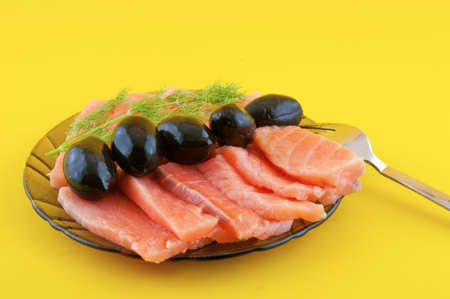 Sliced ââred salt fish and black olives are on a small platterの写真素材