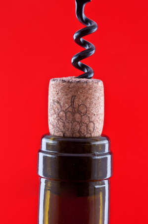 Dark brown bottle with a cork and corkscrew which is screwed into the corkの写真素材