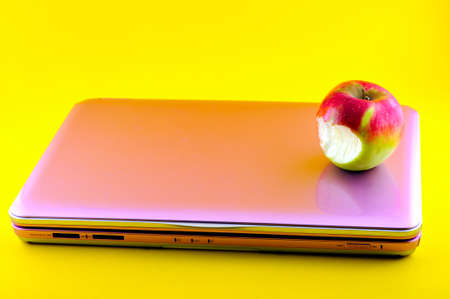 Pink computer that is bitten apple, photographed against a yellow backgroundの写真素材