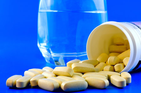 The box with the vitamins that slept on the table beside a glass of water