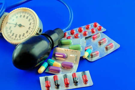 Multi-colored tablets laid on the table near the instrument for measuring blood pressureの写真素材