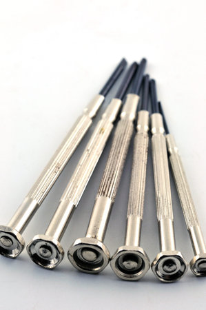 A set of small screwdrivers to repair watches with black tips on the table, against a white...