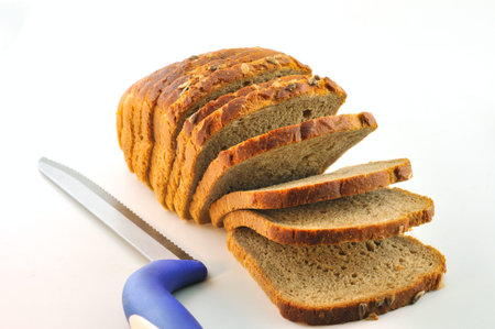 A loaf of rustic bread with sunflower seeds and a knife for cutting bread with a blue pen on the...