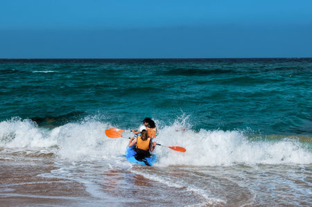 Two girls kayakers run-on trying to overcome a big wave and sail into the open seaのeditorial素材