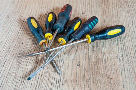 Six different screwdrivers lie heaped on a wooden boardの写真素材