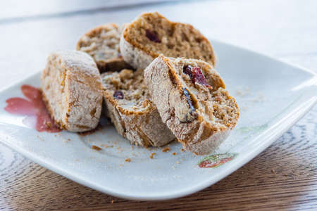 Small depth of field.   
Home rusks with raisins lie in a heap on a white plate on a wooden, kitchen table の写真素材