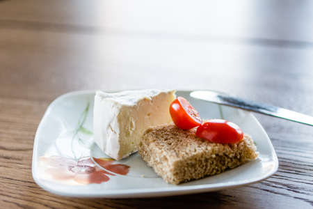 Small depth of field.    A piece of soft cheese and two halves of a tomato on a slice of breadの写真素材