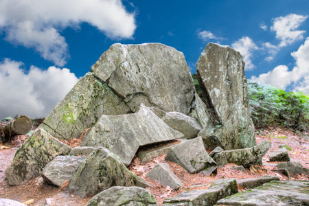 The rock is shot against a background with white clouds against a blue sky