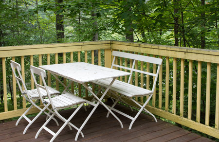 Table and chairs on the veranda of a small house in the forest
