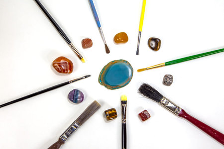 Different Brushes and colored, semi-precious, semi-precious stones, photo on a white background