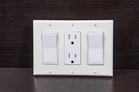 Two switches and a socket in the middle are covered with one triple decorative white overlayの写真素材