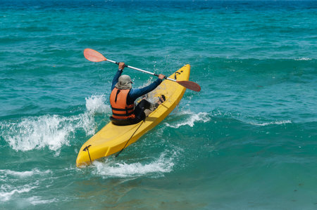 athlete compete in the kayak with sea waves trying to swim away from the shoreの写真素材
