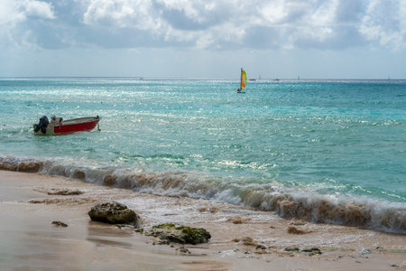 A tethered boat near the shore and a boat with a sail in the warm waters of the Atlantic Oceanの写真素材