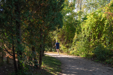 Early September morning, an athlete jogs in city parkの写真素材
