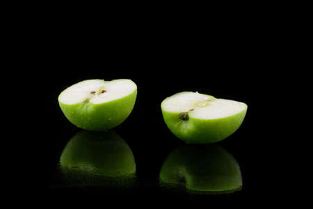 a green sliced apple on blackの写真素材