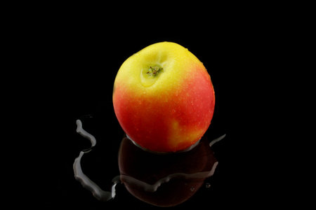 a yellow red apple on black background