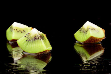 three kiwis with water on black backgroundの写真素材
