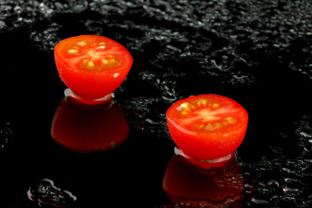 two half red tomatoes on black backgroundの写真素材